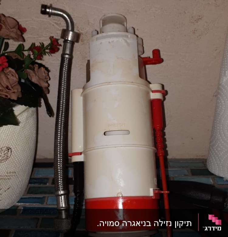 צינור מתכת גמיש ליד מכשיר פלסטיק לבן ואדום